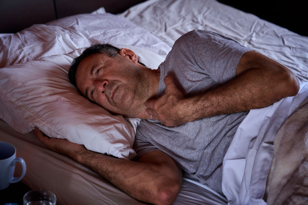 Snugz-trouble-sleeping Man sleeping in bed having difficulty breathing and stressed due to sleep apnea